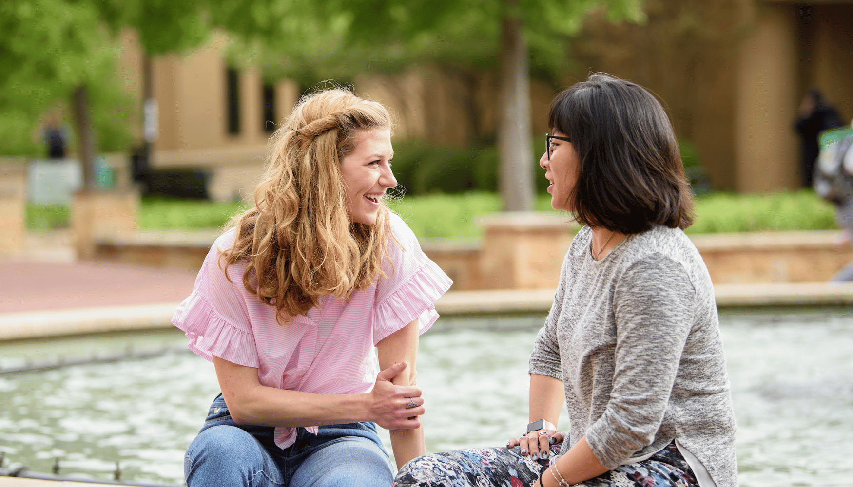 Students sitting at library mall fountain