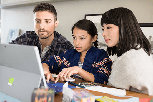 Zwei Erwachsene und ein Kind betrachten einen Laptop