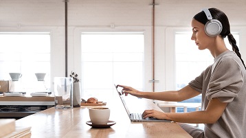 femme portant un casque d’écoute Surface travaillant sur Surface Laptop2 à l’intérieur