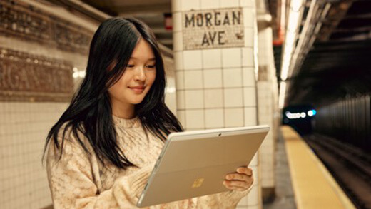 Seorang wanita melihat perangkat Surface Pro nya saat berada di platform kereta bawah tanah.