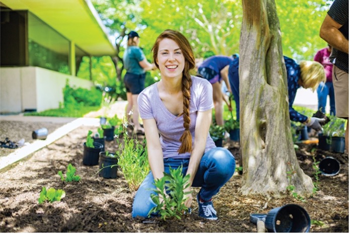 A student transfering aplant from a pot to the soil.