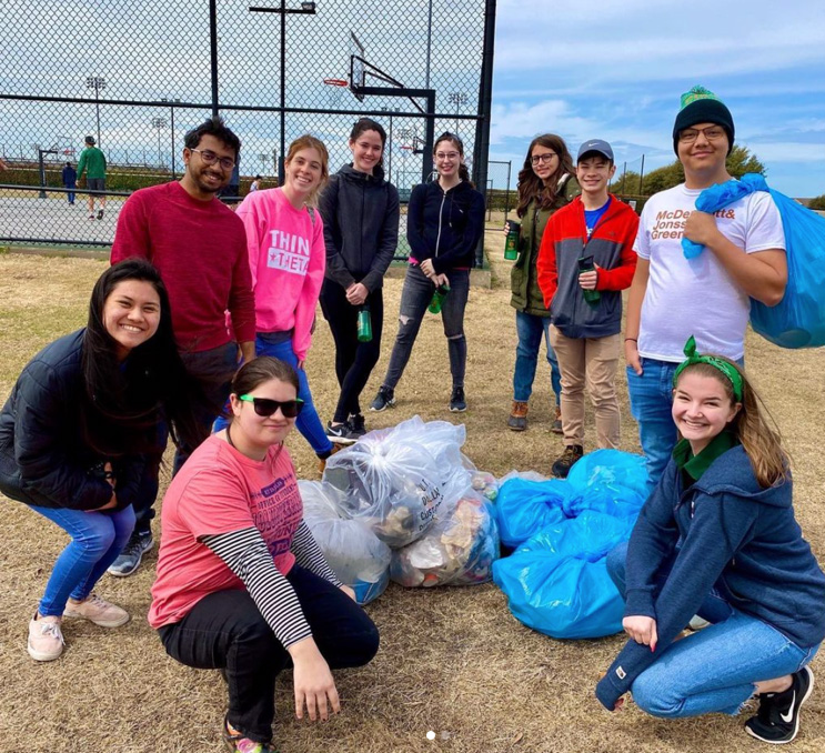 Students gather around bags of collected garbage and recyclables.