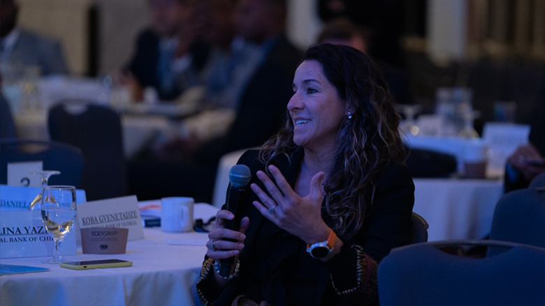 Woman asking question with microphone from table in audience