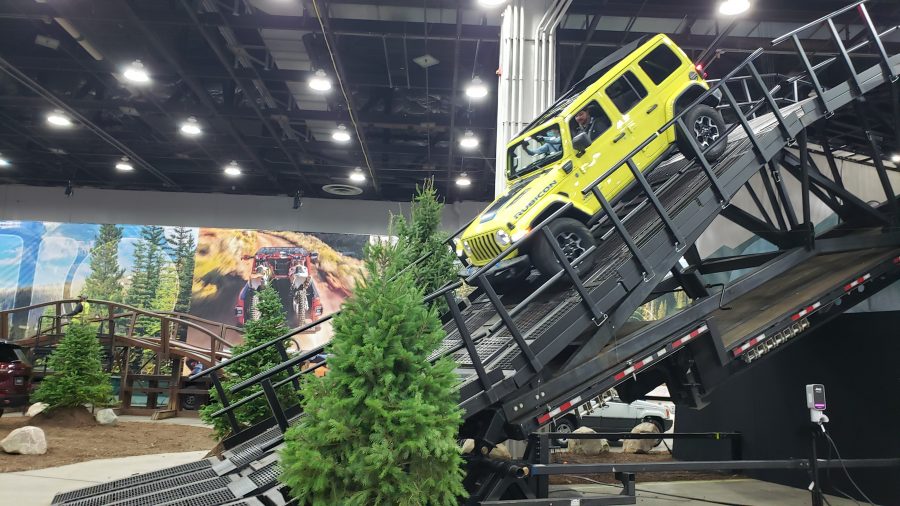 A neon yellow Jeep Wrangler displayed in a steep decline on an indoor set.