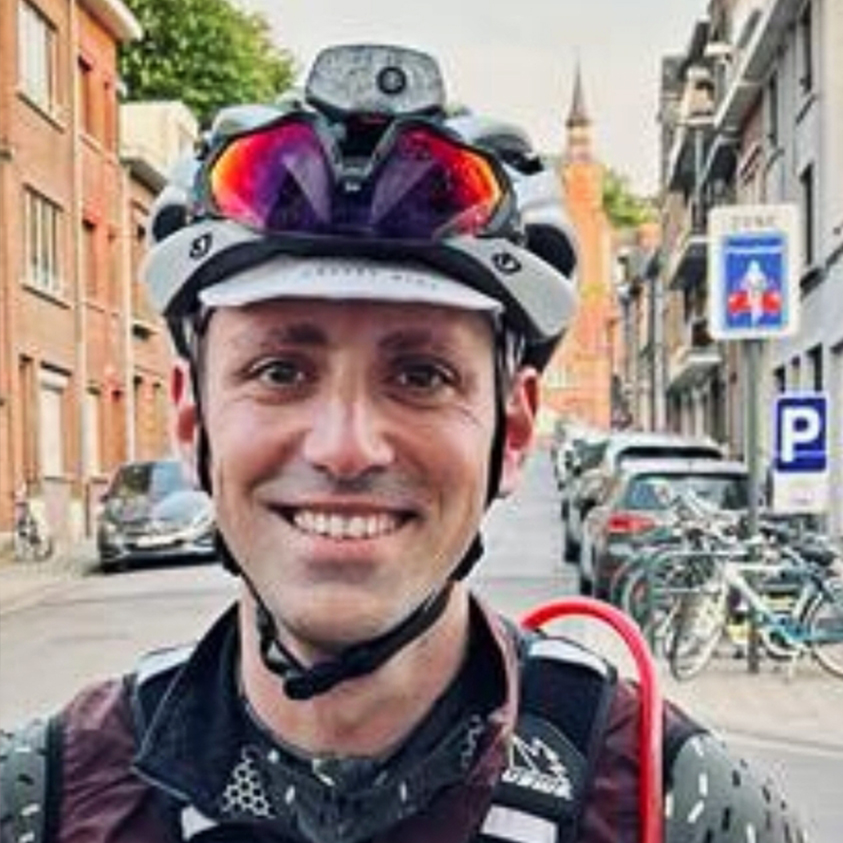 A Cyclist Smiles At The Camera On A City Street