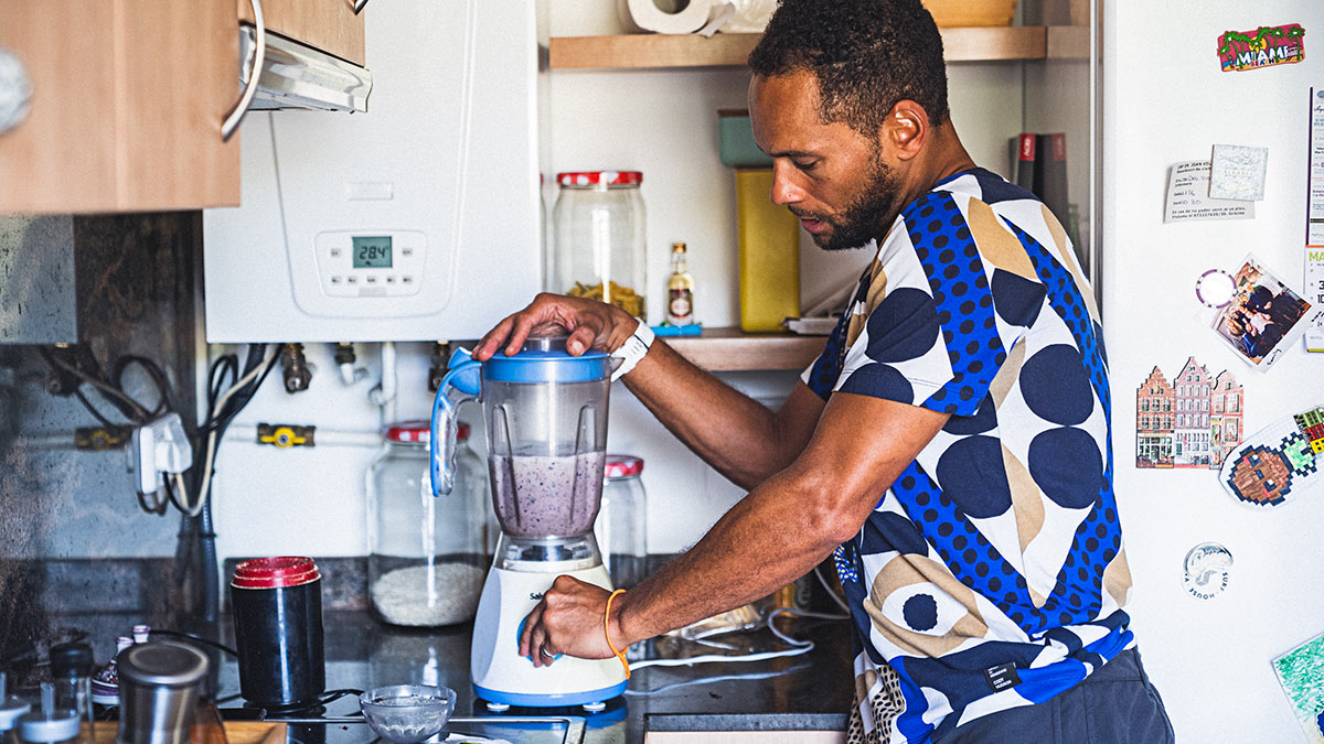 Endurance Athlete Making Post Workout Smoothie In A Blender In A Kitchen To Fuel His Strength Workout