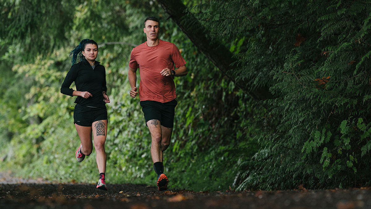 Athlete And Run Coaching Running Together In The Woods