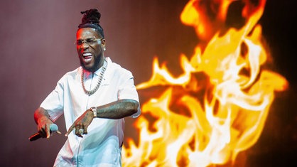 Burna Boy auf der Bühne. Im Hintergrund brennt ein digitales Feuer.