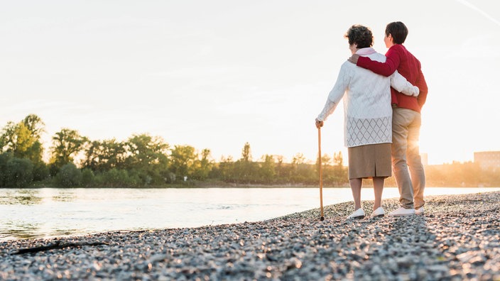 Frau mit ihrer alten Mutter am Ufer eines Flusses