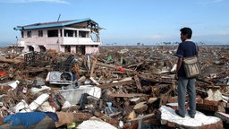 Ein Mann steht zwischen den Trümmern seines Hauses und Heimatortes in Banda Aceh nach dem Tsunami von 2004