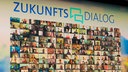 auf einer Videowand sind unter der Überschrift "Zukunftsdialog" viele Videoaufnahmen von Menschen zeilenweise angeordnet