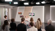 Besucherführerin erläutert einer Menschengruppe ein Fernsehstudio