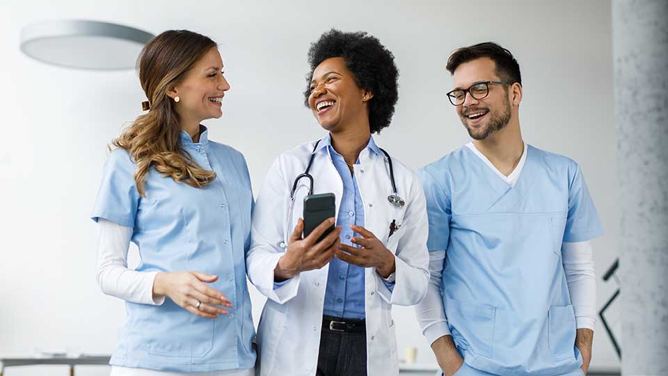 three physicians laughing together while walking