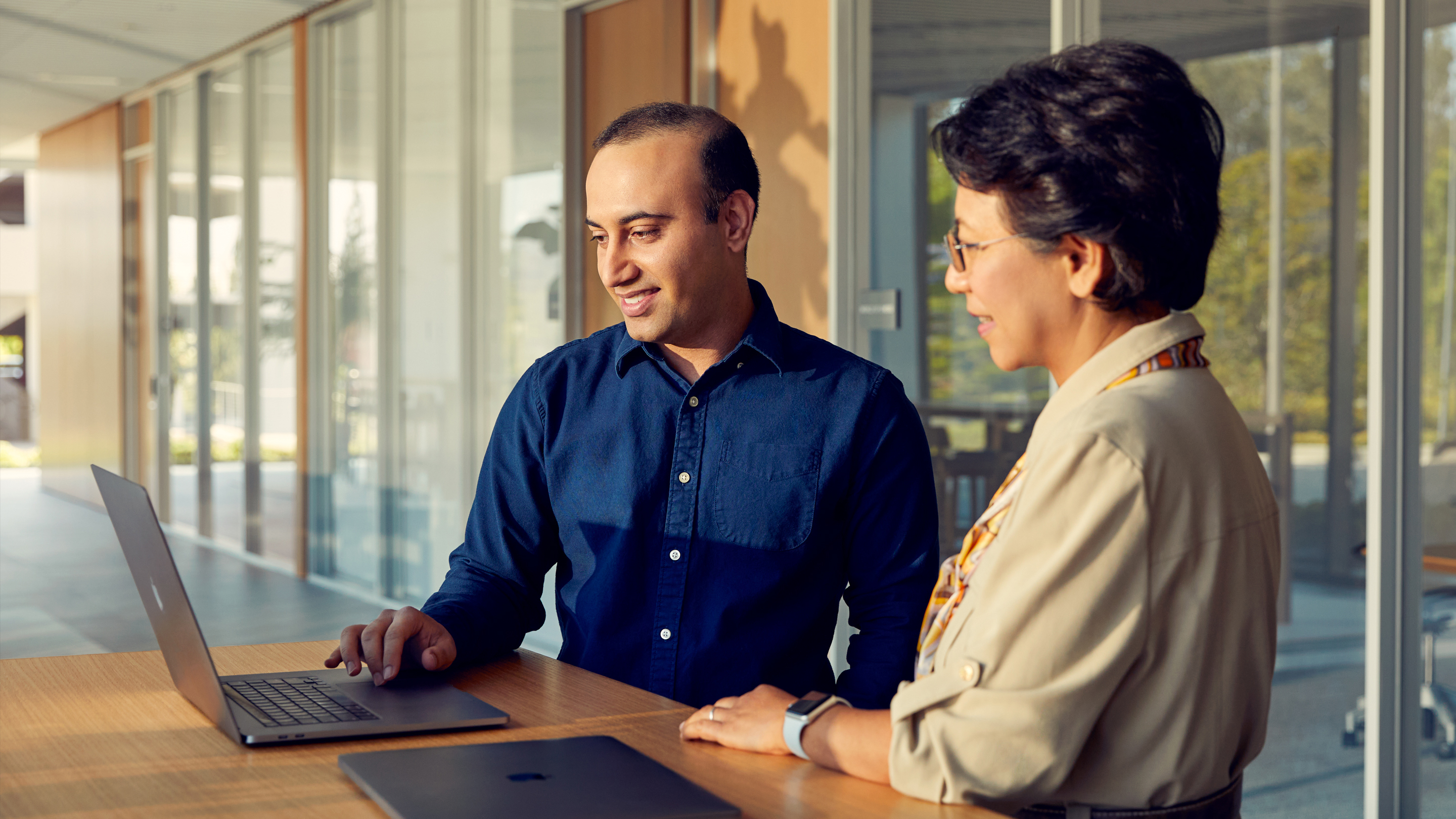 Two Apple San Diego employees collaborating with laptops.