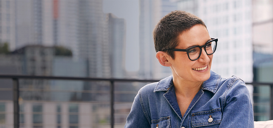 Sophie, seated in front of a cityscape, smiling and looking off to the side.