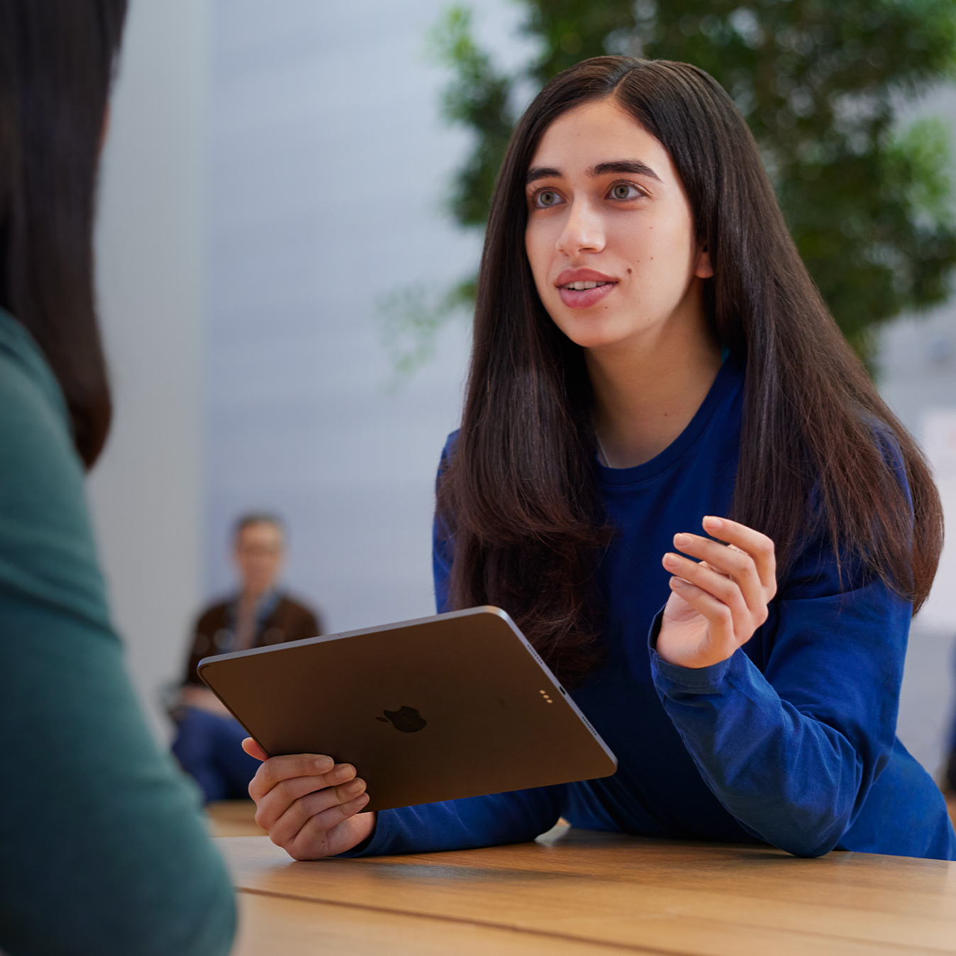 Serene holding an iPad and talking with a customer.