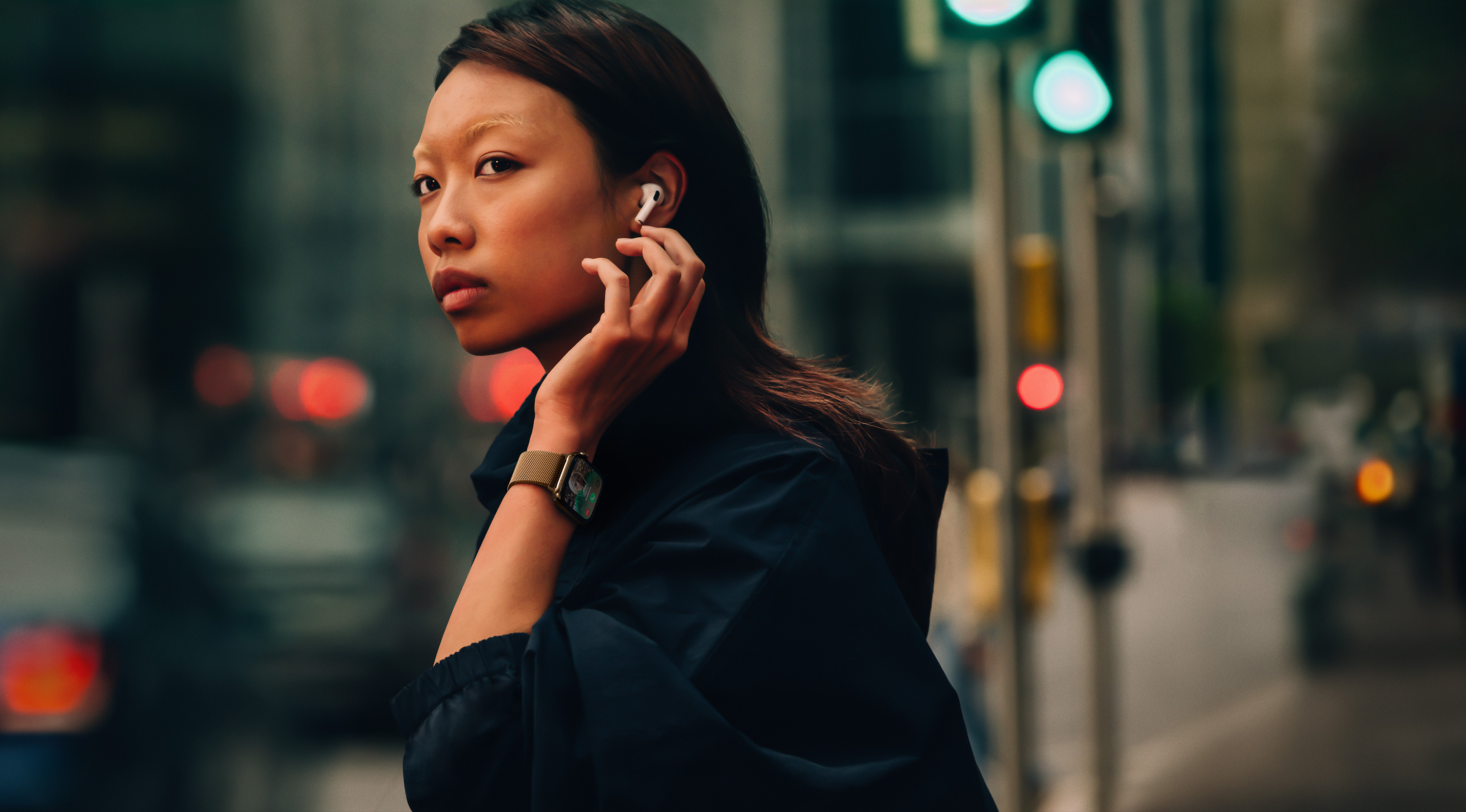 Seorang perempuan yang mengenakan Apple Watch Series 10 dan AirPods di jalan.