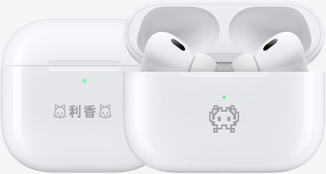 絵文字の例が刻印された2つのAirPods 4の充電ケース。1つには「利香」というテキストの両側に猫の絵文字が刻印され、もう1つにはカニの絵文字が刻印されている。