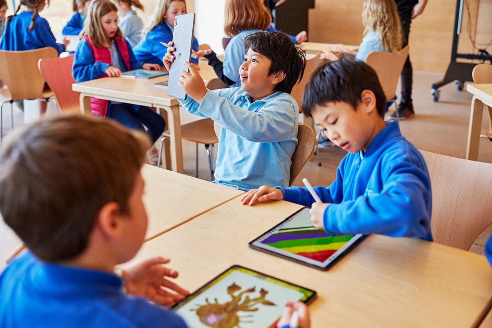 Young students at table using iPad Pro and Apple Pencil.