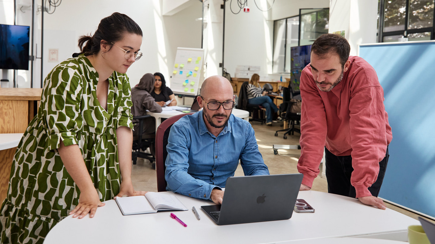 Trois personnes de l'Apple Foundation Program en France devant leur MacBook dans une salle de classe.