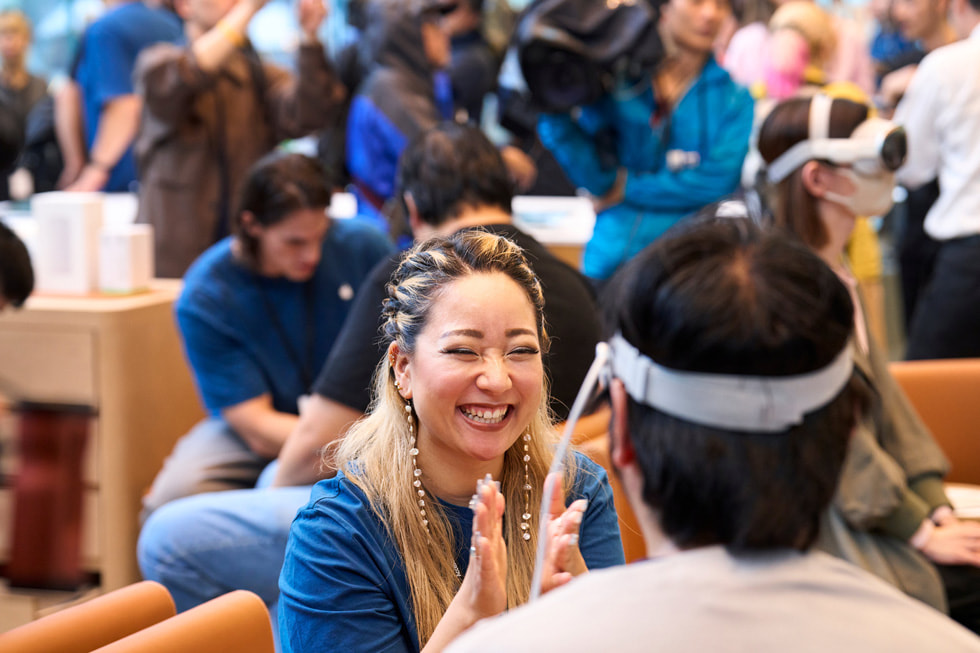 A team member in the store’s Demo Zone smiles while facing a customer wearing Apple Vision Pro.