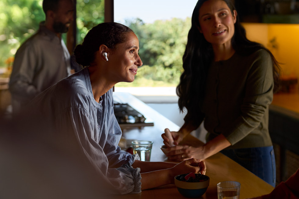 A lifestyle shot shows a person wearing AirPods Pro 2 while listening to other people.