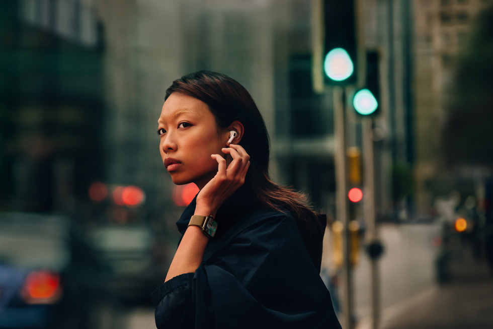 圖為一名佩戴 AirPods 4 和 Apple Watch Series 10 的使用者走在城市街道上。