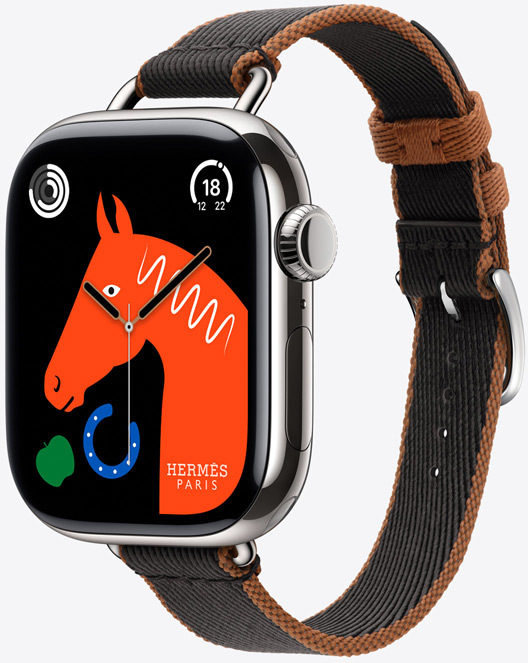 Angled view of the new Twill Jump Attelage Single Tour strap in Noir/Gold (black with gold trim) with “Lucky Horse” watch face featuring an orange horse’s head, a green apple and a blue horseshoe.