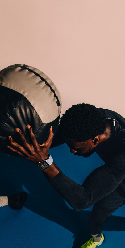 A man wearing an Apple Watch Series 10 holds a medicine ball during a workout.