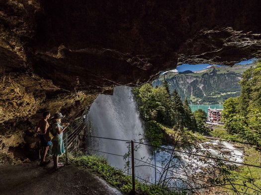 Ein Paar bestaunt von einer Höhle aus die tosenden Wassermassen der Giessbachfälle