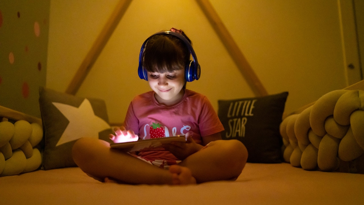 Girl sitting Criss cross applesauce and holding a tablet.