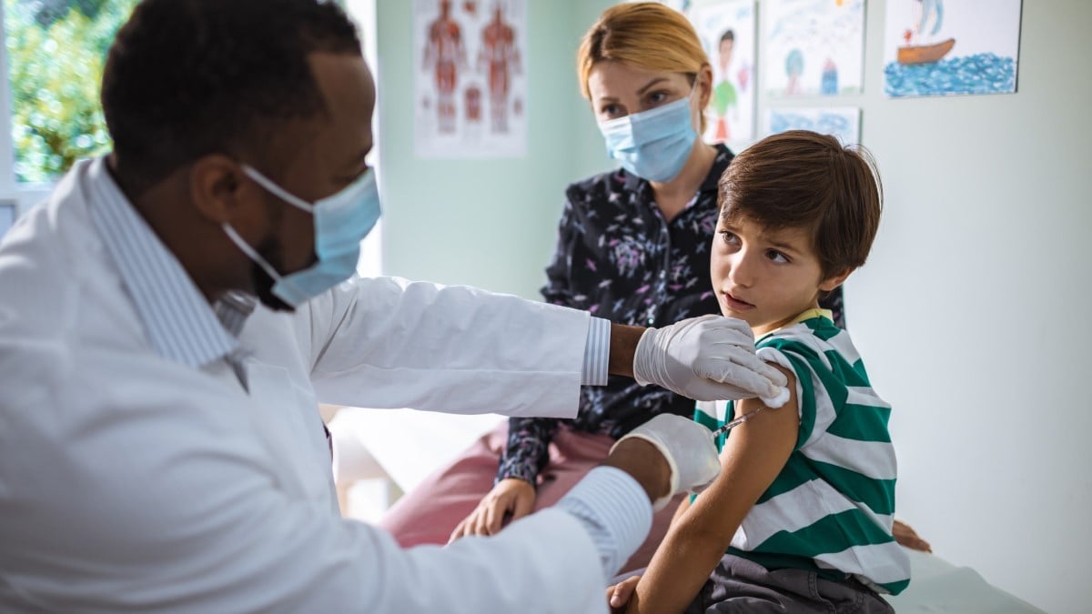 un médico que le administra la vacuna contra el VPH a un niño mientras su madre mira