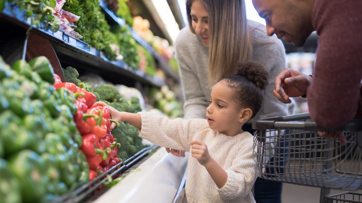 Una madre, un padre y un niño comprando verduras frescas