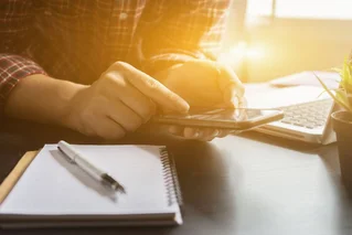 Person with paper, pen, and phone