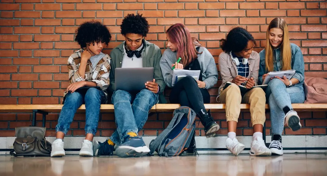 Un groupe d'enfants assis ensemble et regardant des ordinateurs portables et des documents.