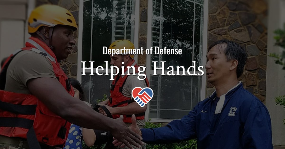 Army rescuer shakes hands with a civilian while standing in floodwaters.