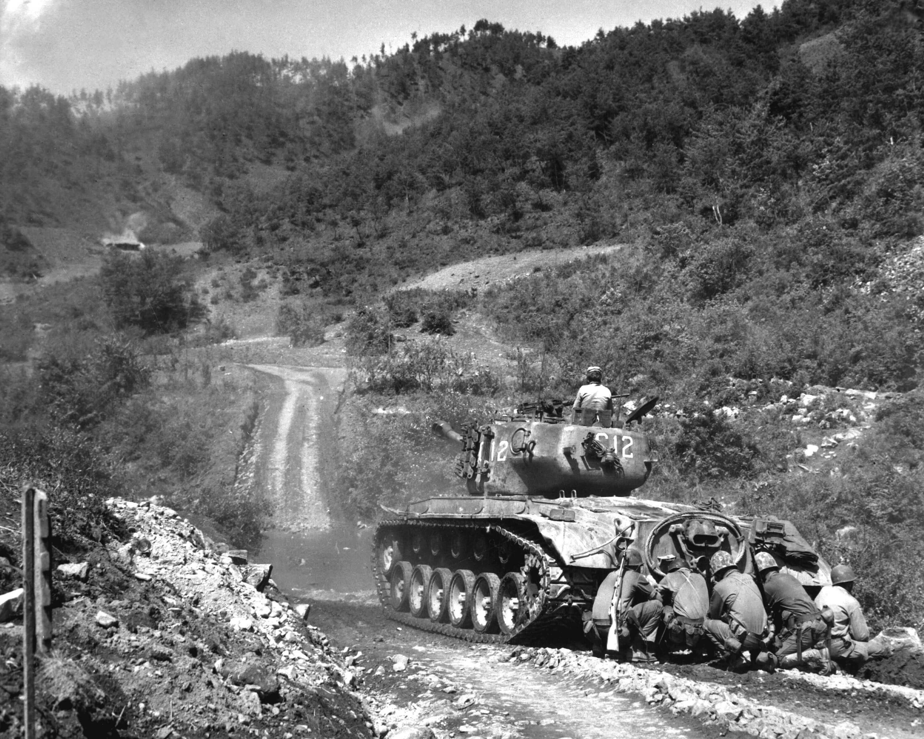 Soldier crouching behind a tank for protection