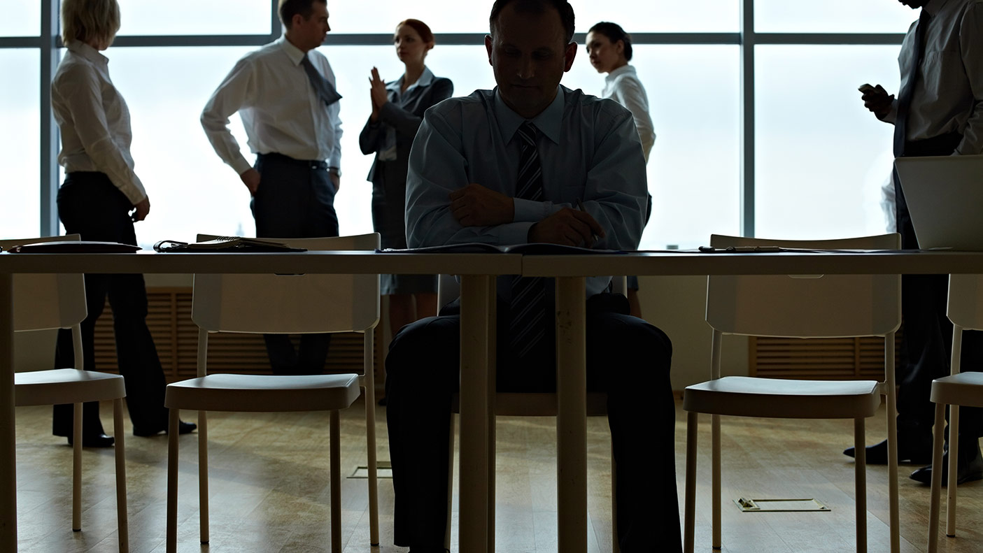 Male leader reading document table with business people cooperating with each other behind