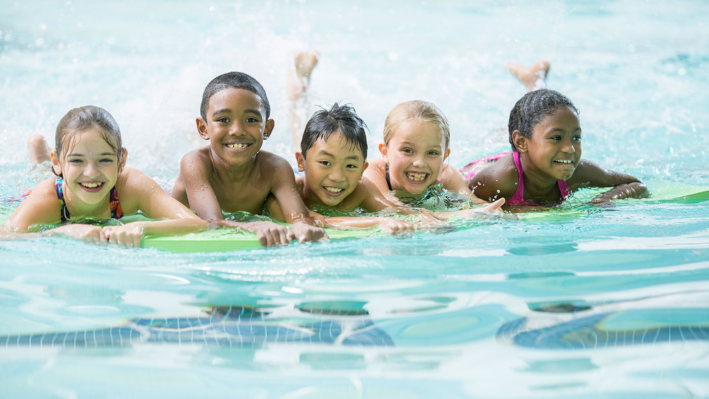 5 children are lined up in a public swimming pool.