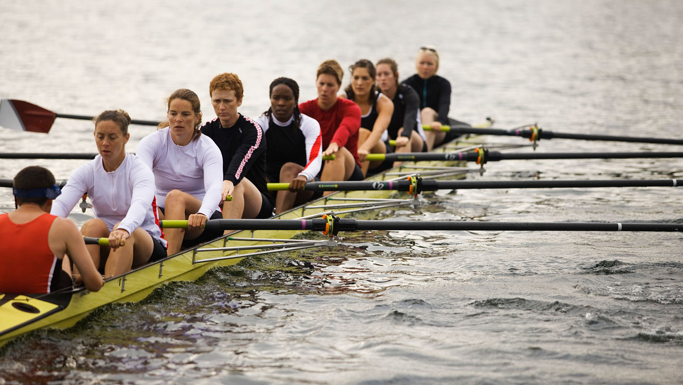 a mixed gender rowing team on a river, rowing.