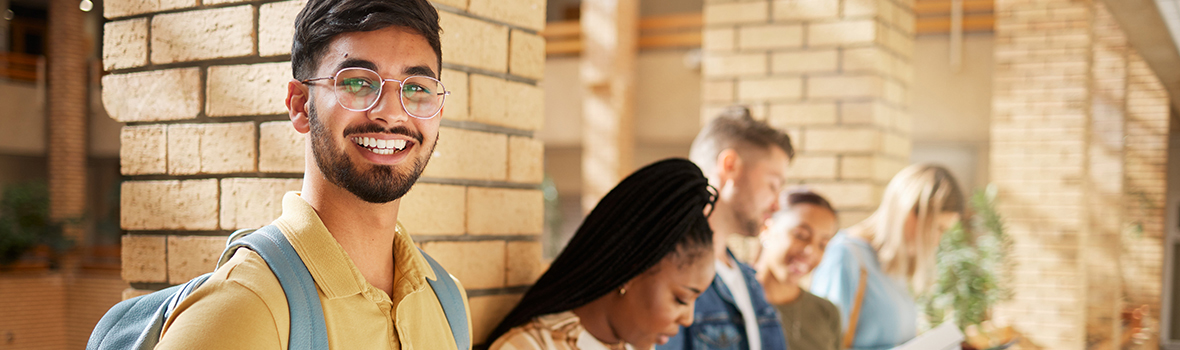 Smiling male student on campus with friends