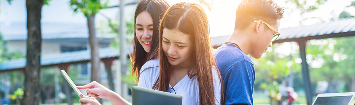 Three students sitting on the lawn