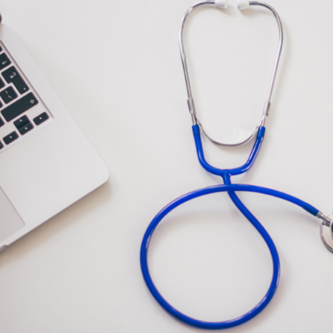 A stethoscope and a laptop placed on a desk.