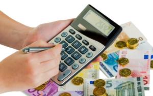 Euro coins and banknotes, a person holding a calculator and a pen