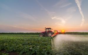 Tractor spraying pesticides on vegetable field with sprayer at spring