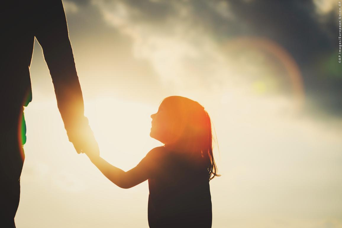 Silhouette of little girl holding parent hand at sunset ©AP images/European Union - EP