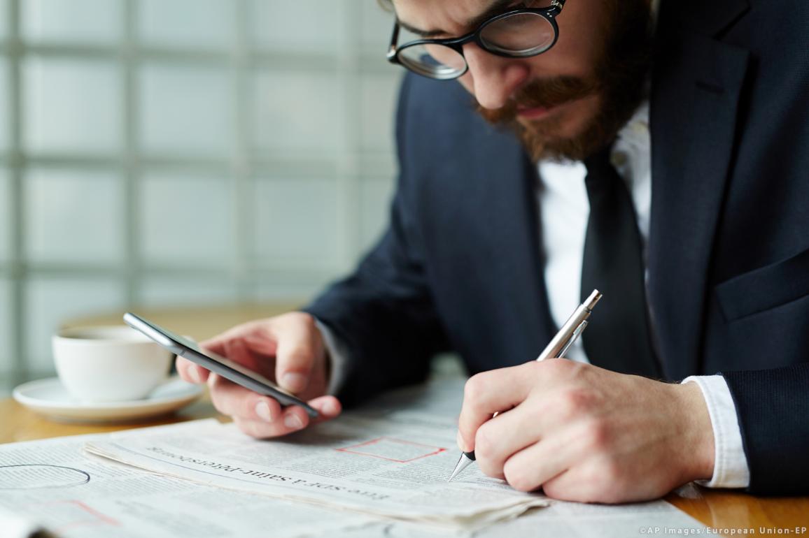 A person is looking for an employment on a newspaper job ads page © AP Images/European Union - EP