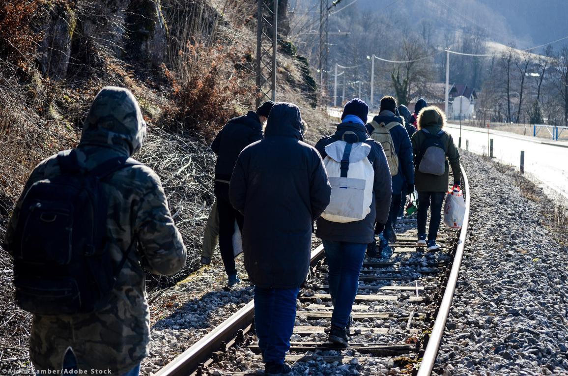 Group of migrants walking along railway tracks. ©Ajdin Kamber/AdobeStock