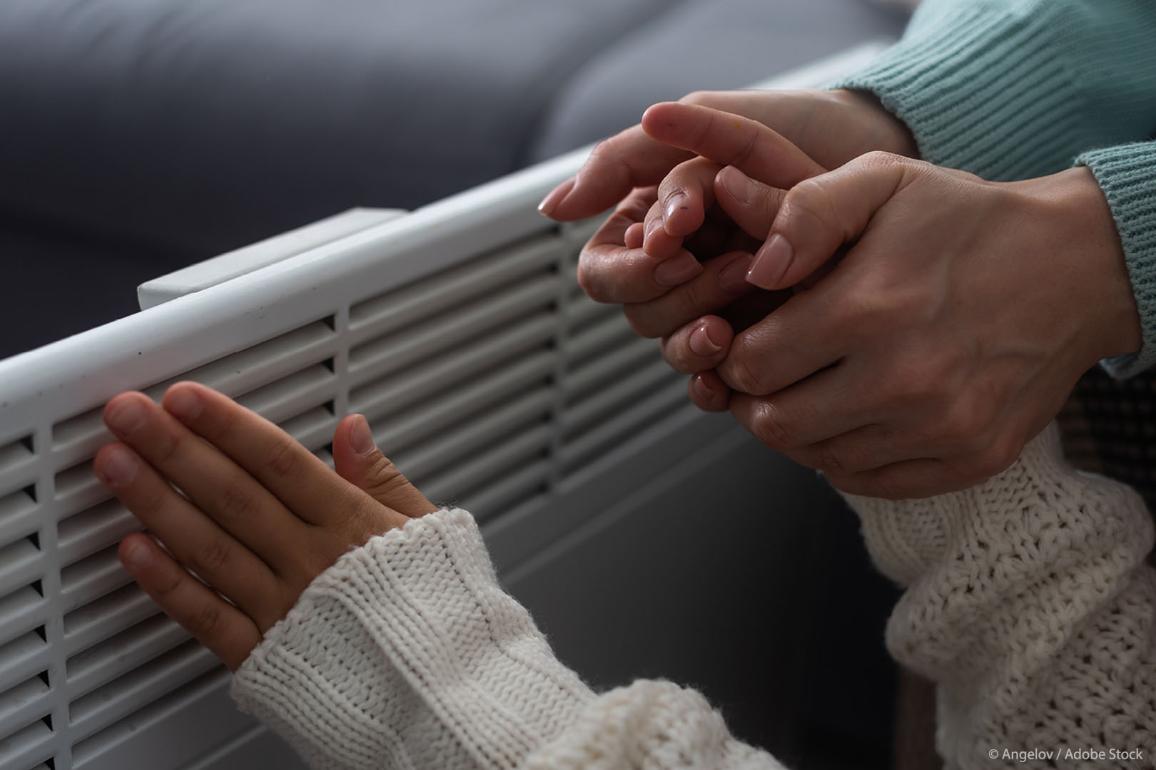 Two pairs of women's hands next to a heater