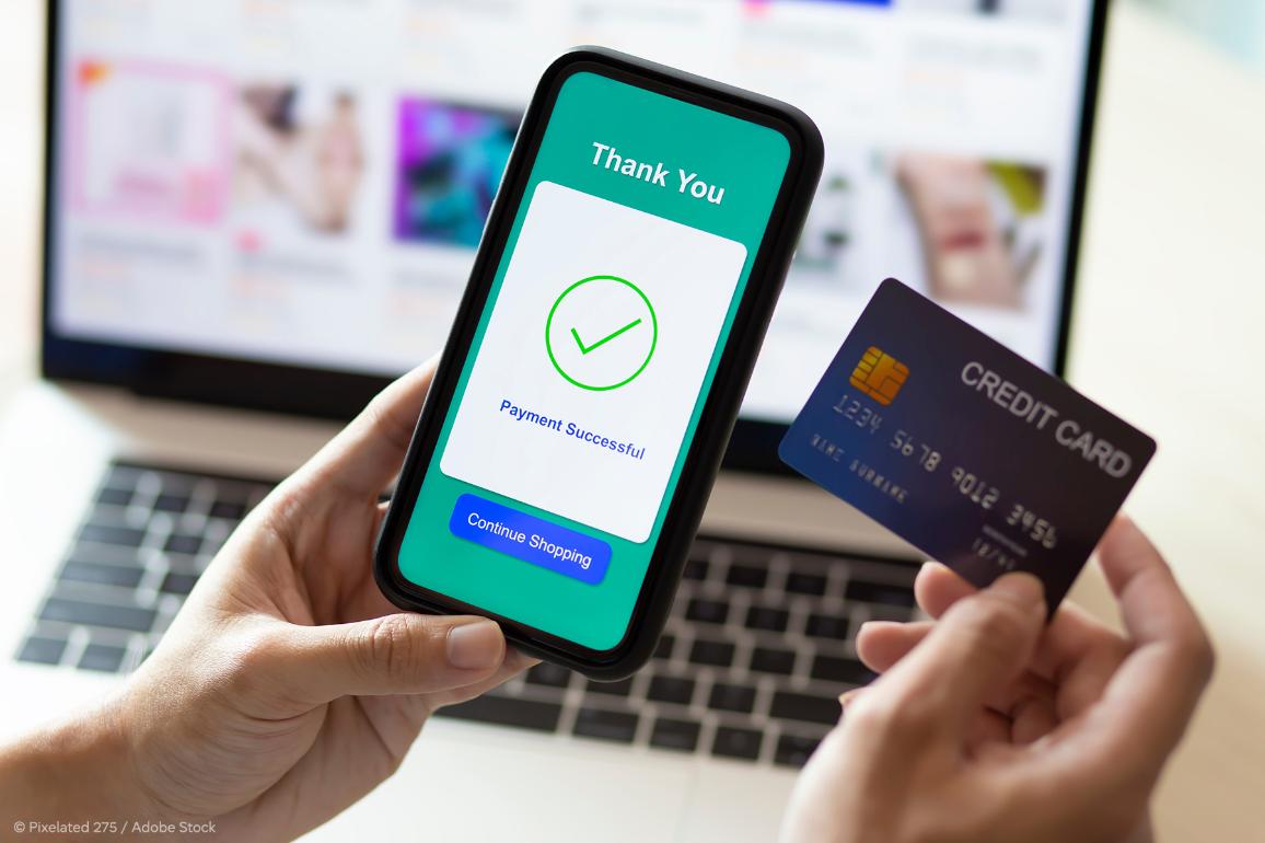 Close-up on a hand holding a mobile phone. We can see on the screen a payment has been successful.